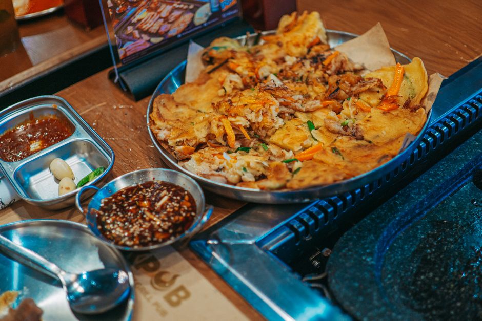 Korean bindaetteok mung bean pancake cooking on griddle Gwangjang